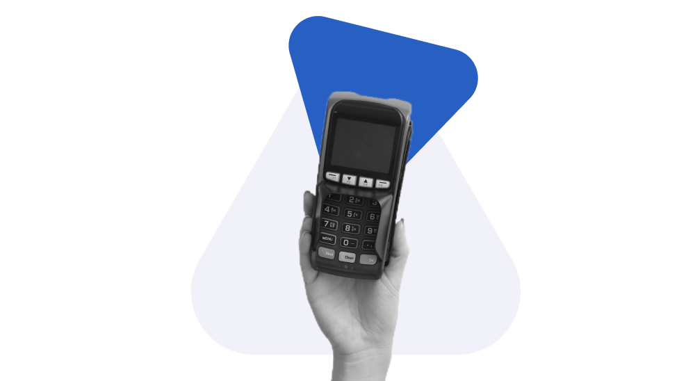 Mão segurando uma maquininha de cartão fazendo referência ao mercado de adquirência